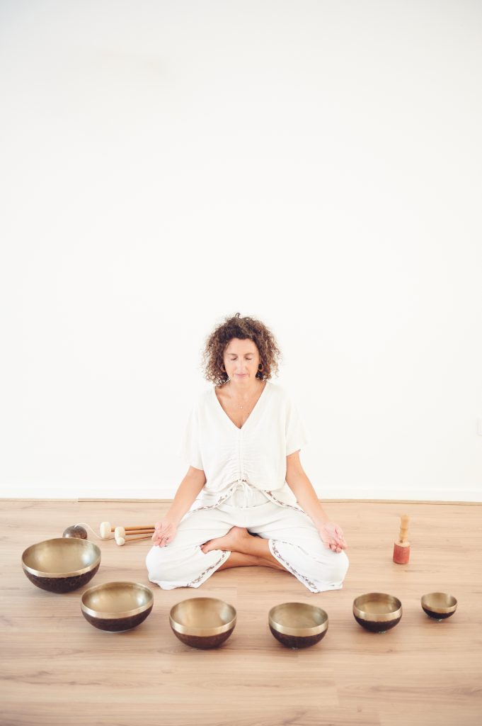 manuela sentada meditando con cuencos tibetanos alrededor