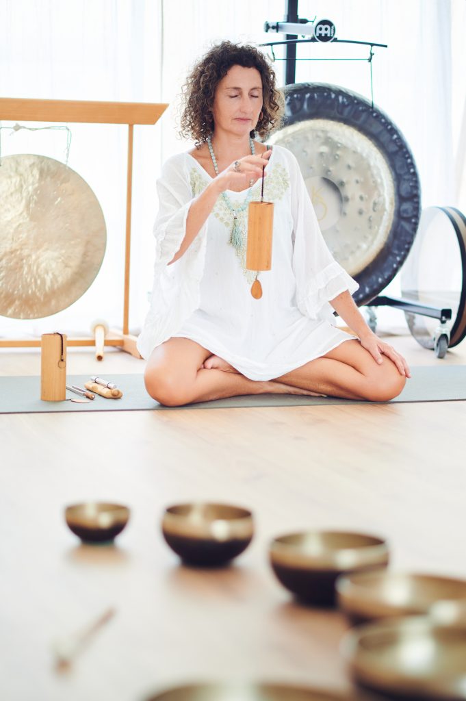 manuela sentada en Ram tocando un instrumento delante de los gongs, se ven los cuencos tibetanos